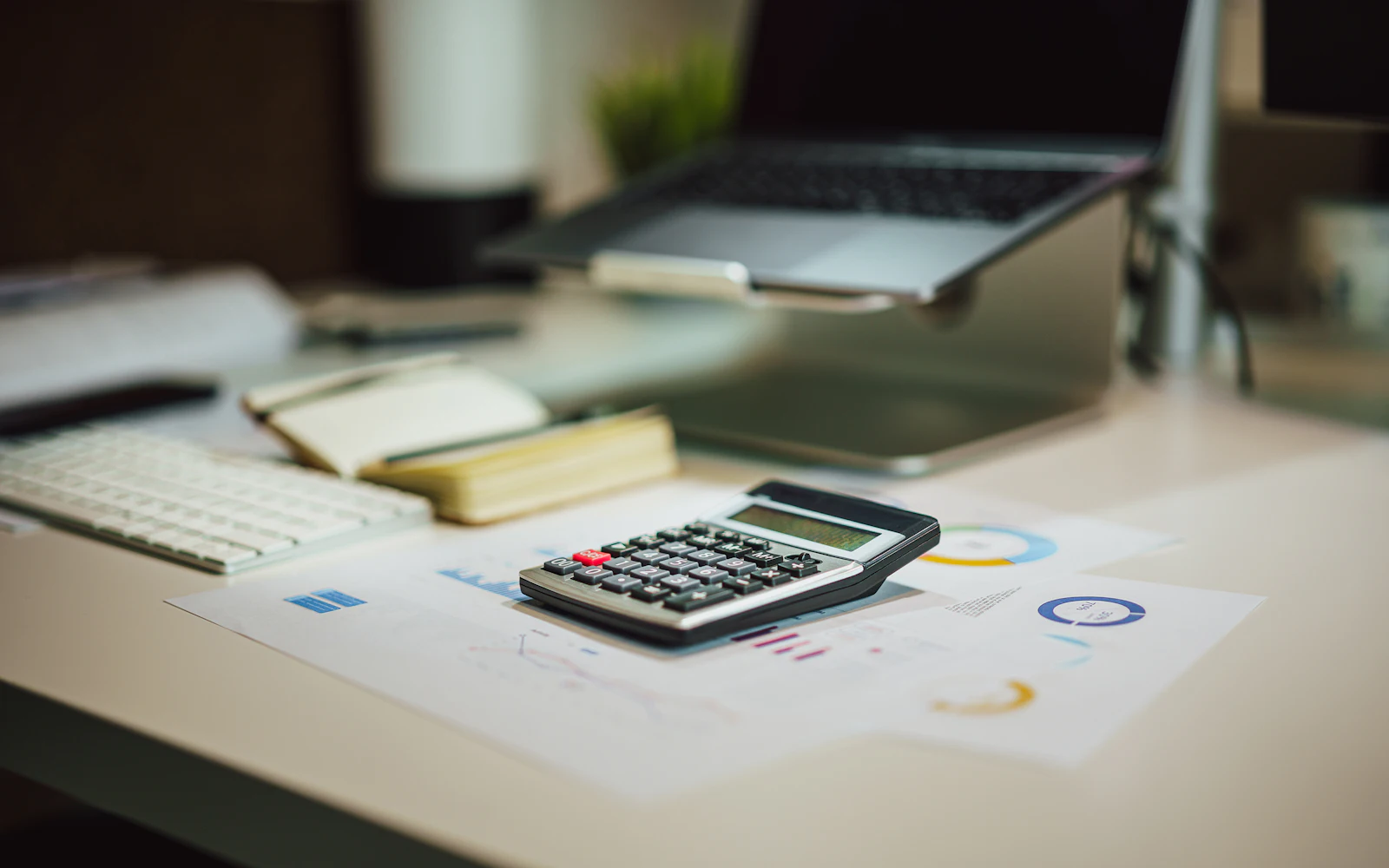 Calculator, laptop and financial papers on a desk
